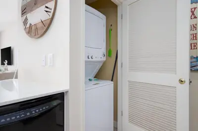 a white kitchen with a microwave and a refrigerator at Water Park On-Site! 2 Beachfront Master Suites! Corner Balcony Views! in Panama City Beach
