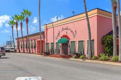 a pink building on the side of a street with palm trees at Water Park On-Site! 2 Beachfront Master Suites! Corner Balcony Views! in Panama City Beach