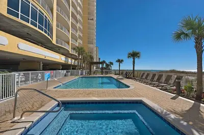 a swimming pool in front of a building with palm trees at Beautiful Ocean Views! 2-Bedroom, 2-Bathroom! Resort Pools! in Panama City Beach