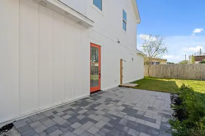 a white house with a red door and a yard at Brand NEW Expansive Coastal Home w/ Custom Furnishings Sleeps 15 in Panama City Beach