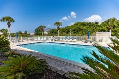 a swimming pool with chairs and palm trees at 140 Feet To White Sandy Beaches! Newly Renovated! Pool! Grill! in Panama City Beach