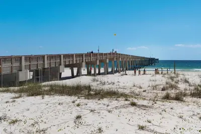 a pier on a beach next to the ocean at 140 Feet To White Sandy Beaches! Newly Renovated! Pool! Grill! in Panama City Beach