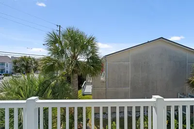 a white fence in front of a house with palm trees at 140 Feet To White Sandy Beaches! Newly Renovated! Pool! Grill! in Panama City Beach