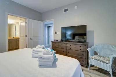 a bedroom with towels on a bed with a television at Gulf Front Master Suite! Directly On The Beach! 3 BR / 2 BA! Sleeps 8! in Panama City Beach