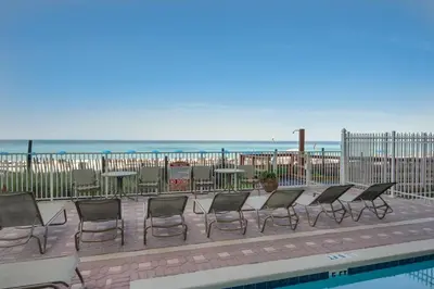a row of chairs and tables next to a pool at Gulf Front Master Suite! Directly On The Beach! 3 BR / 2 BA! Sleeps 8! in Panama City Beach