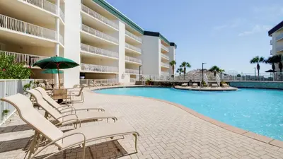 a swimming pool with lounge chairs and an umbrella at Stunning 2 BR/2 BA Third Floor Unit Directly On Santa Rosa Beach! Sleeps 6! in Santa Rosa Beach