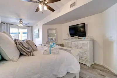 a living room with a large bed with a tv at Stunning 2 BR/2 BA Third Floor Unit Directly On Santa Rosa Beach! Sleeps 6! in Santa Rosa Beach