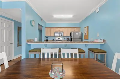a kitchen with blue walls and a table and chairs at Large Balcony! Gulf Front Master Suite! Many Amenities On-Site! in Panama City Beach