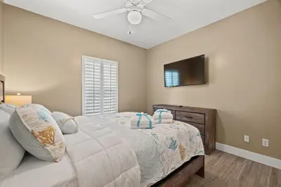 a bedroom with a bed and a ceiling fan at Charming Retreat, a Short Walk to Laguna Beach, with Room for 10! in Panama City Beach