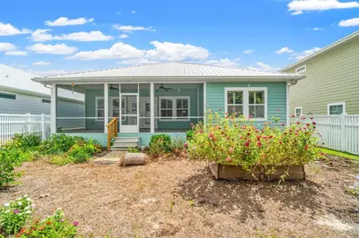 a blue house with flowers in a yard at Charming Retreat, a Short Walk to Laguna Beach, with Room for 10! in Panama City Beach