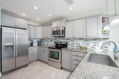 a kitchen with white cabinets and a stainless steel refrigerator at Spacious Waterfront Townhome - Just A Short Walk to Pier Park in Panama City Beach