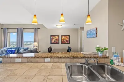 a kitchen with a sink and a living room at Across From The Beach! Near Pier Park & Dining! Sleeps 6! 2 BR / 2 BA! in Panama City Beach