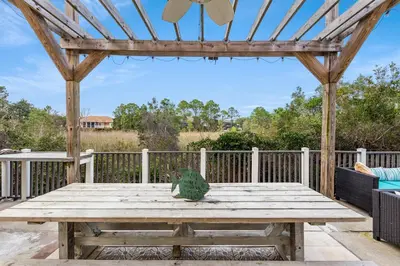 a bird sitting on a wooden picnic table on a deck at Algun Dia - Plush Family-Friendly Home - A Block from Beach in Panama City Beach