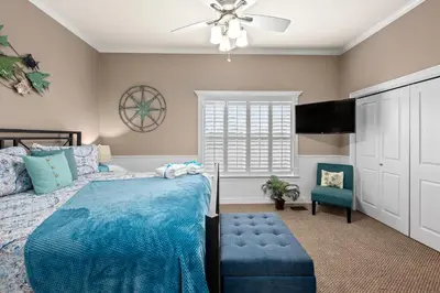 a bedroom with a blue bed and a ceiling fan at Algun Dia - Plush Family-Friendly Home - A Block from Beach in Panama City Beach