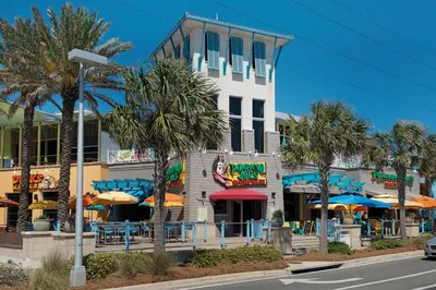 a building with tables and umbrellas in front of it at Algun Dia - Plush Family-Friendly Home - A Block from Beach in Panama City Beach