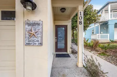 a sign on the side of a house with a door at Algun Dia - Plush Family-Friendly Home - A Block from Beach in Panama City Beach