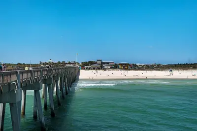 a pier over the ocean with a beach and people at 120 Palm Beach Dr A - La Casa Turquesa in Panama City Beach