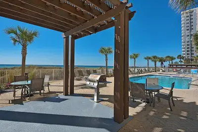 a patio with a table and chairs next to a pool at NEW PROPERTY! Vacation Right on the Gulf in Sand & Seafoam Villa Sleeps 6! in Panama City Beach