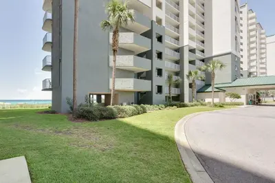 a large apartment building with palm trees and a sidewalk at Beautiful Long Beach Condo unit 1-1206! TWO Gulf Masters! in Panama City Beach