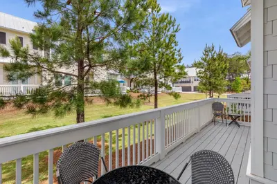 a balcony with chairs and tables and trees at 24 York Lane | Edgewater Escape in Inlet Beach