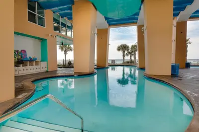 a swimming pool in a building with blue water at Gulf Front! 2 BR 2 BA! 11th Floor condo + Condo Amenities! in Panama City Beach