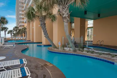 a swimming pool with palm trees and lounge chairs at Gulf Front! 2 BR 2 BA! 11th Floor condo + Condo Amenities! in Panama City Beach