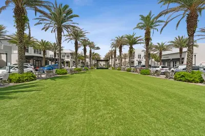 a large lawn in front of a parking lot with palm trees at The FUN Orange home in a Great Location with bonus GAME room in Rosemary Beach