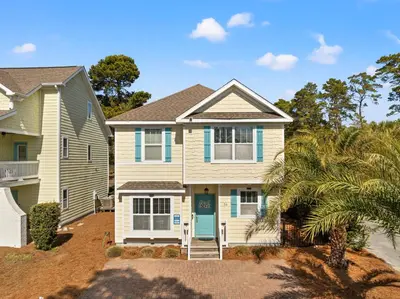 a house with a palm tree in front of it at The FUN Orange home in a Great Location with bonus GAME room in Rosemary Beach