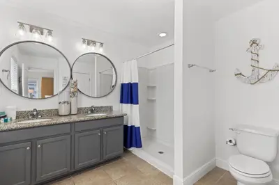 a bathroom with a sink and a toilet and a mirror at The FUN Orange home in a Great Location with bonus GAME room in Rosemary Beach