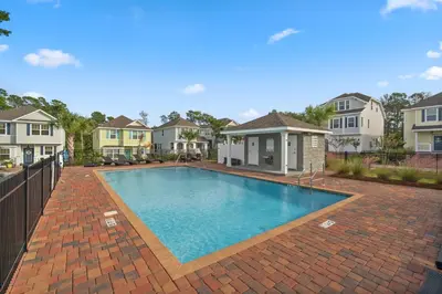 a large swimming pool in a yard with houses at The FUN Orange home in a Great Location with bonus GAME room in Rosemary Beach