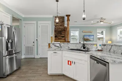 a kitchen with white cabinets and a stainless steel refrigerator at Three Master Bedrooms! Easy Beach Access! Gulf Views in Panama City Beach
