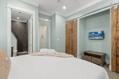 a bedroom with a white bed and a wooden door at Three Master Bedrooms! Easy Beach Access! Gulf Views in Panama City Beach