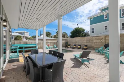 a patio with a table and chairs on a brick patio at Three Master Bedrooms! Easy Beach Access! Gulf Views in Panama City Beach