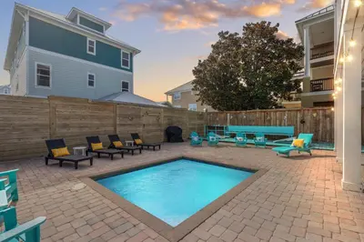 a patio with a pool and chairs and a fence at Three Master Bedrooms! Easy Beach Access! Gulf Views in Panama City Beach