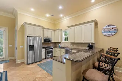 a kitchen with white cabinets and a stainless steel refrigerator at Luxury Home in Palmeira Village w Private Pool, Steps to Beach for 12! in Santa Rosa Beach