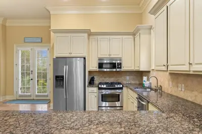 a kitchen with white cabinets and a stainless steel refrigerator at Luxury Home in Palmeira Village w Private Pool, Steps to Beach for 12! in Santa Rosa Beach