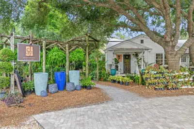 a display of plants in a garden in front of a house at Luxury Home in Palmeira Village w Private Pool, Steps to Beach for 12! in Santa Rosa Beach