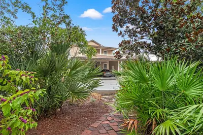 a house with a lot of plants in front of a driveway at Luxury Home in Palmeira Village w Private Pool, Steps to Beach for 12! in Santa Rosa Beach