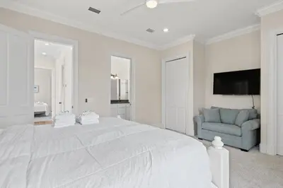 a white bedroom with a large bed and a blue chair at Feel Like Luxury Vacationing in this Private Community in Seagrove on 30A in Santa Rosa Beach