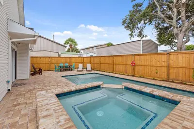 a swimming pool in a backyard with a wooden fence at Expertly Decorated Family Home, Steps to Beach w/ a Private Heated Pool & Spa! in Panama City Beach