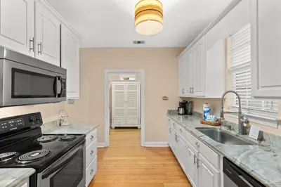 a kitchen with white cabinets and a black stove top oven at Expertly Decorated Family Home, Steps to Beach w/ a Private Heated Pool & Spa! in Panama City Beach