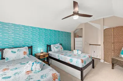 a bedroom with two beds and a blue wall at Expertly Decorated Family Home, Steps to Beach w/ a Private Heated Pool & Spa! in Panama City Beach