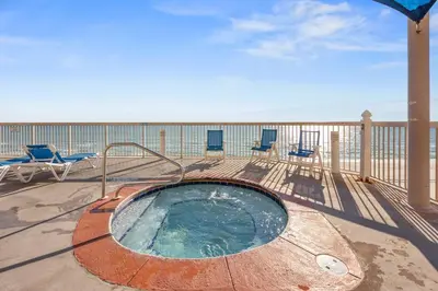 a hot tub on a deck with chairs on the beach at Gulf Front Master Bedroom, 2 Pools & Hot Tubs, Sleeps 8 in Panama City Beach