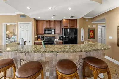 a kitchen with a large island with bar stools at Gulf Front Master Bedroom, 2 Pools & Hot Tubs, Sleeps 8 in Panama City Beach