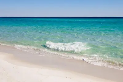 a beach with a wave breaking on the shore at 12 Periwinkle Ln - Beach Blessings in Santa Rosa Beach