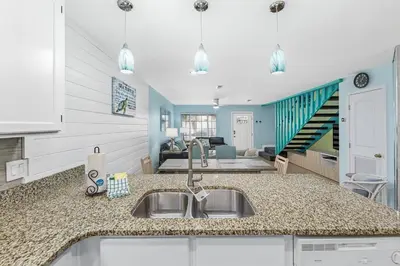 a kitchen with a sink and a living room at Short Walk to The Beach! Community Pool! Sleeps 6! in Panama City Beach
