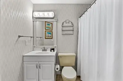 a white bathroom with a toilet and a sink at Short Walk to The Beach! Community Pool! Sleeps 6! in Panama City Beach