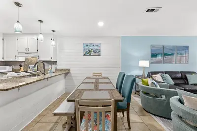 a kitchen and living room with a table and chairs at Short Walk to The Beach! Community Pool! Sleeps 6! in Panama City Beach