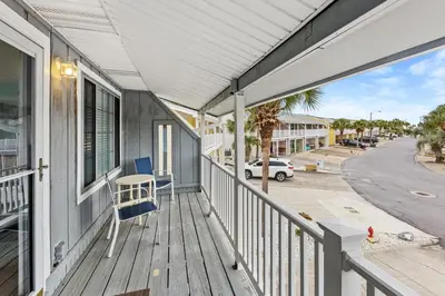 a porch with a blue chair on a house at Short Walk to The Beach! Community Pool! Sleeps 6! in Panama City Beach
