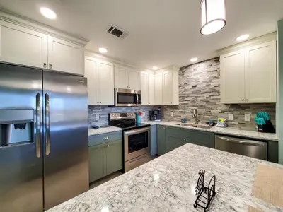a kitchen with white cabinets and a stainless steel refrigerator at Laketown Wharf 911 - Luxury at the Wharf in Panama City Beach
